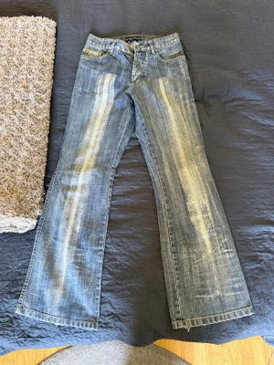 Vintage- Blå bootcut jeans - Säljer ett par blå bootcut jeans med tydliga slitningar framtill och baktill. Jeansen har klassisk femficksdesign, låg midja och vida ben. Storlek W30 L32. Vid funderingar eller liknande är det bara att höra av sig! 