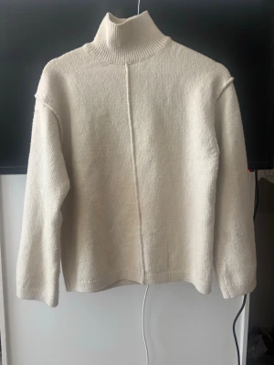 Beige polotröja från H&M - Säljer en beige stickad polotröja från H&M. Tröjan har hög krage, lång ärm och en rak passform med en dekorativ söm framtill. Perfekt för lager på lager och enkel att matcha med olika outfits. Storlek xxs men oversize skulle säga S/M