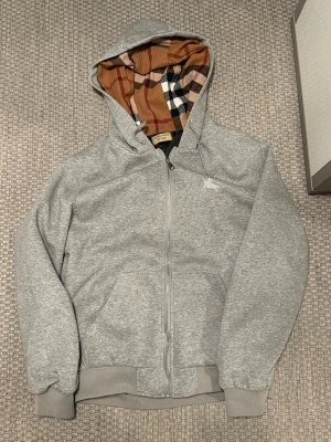 Grå Burberry zipper tröja. - Grå riktigt skön och stilig Burberry tröja, enkel zipper och bra passform. Ny liknande skick och inga fel någonstans. Storlek är större an vad det står på tröjan och passar bättre för storlek M. Hör gärna av vid frågor eller snabba affärer.👌🏽