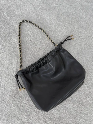 Svart väska - Säljer denna otroliga svarta väska från H & M som inte längre går att köpa. Väskan är aldrig använd så i helt nyskick. Väskan är lagom storlek som rymmer vardagliga saker. 