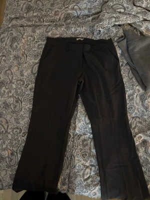 Svarta raka kostymbyxor - Snygga mörkgråa kostymbyxor med raka ben och klassisk passform. Byxorna har bälteshällor och sidofickor. Perfekta för en stilren look. Byxorna är i storlek 44 men passar bra på även 42