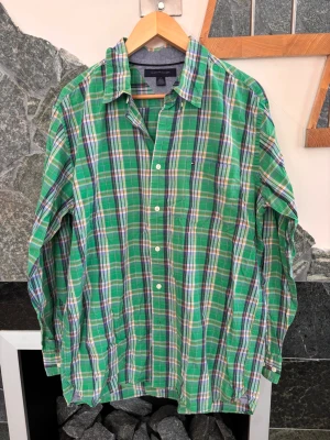 Grön rutig skjorta Tommy Hilfiger - Säljer en grön rutig skjorta från Tommy Hilfiger i storlek L. Skjortan har klassisk krage, långa ärmar och knäppning framtill. Tillverkad i mjuk bomull och har små detaljer i blått, vitt och orange i rutmönstret.