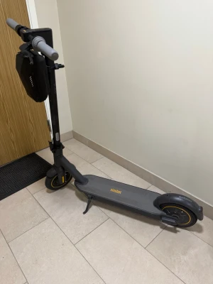Elscooter Ninebot med förvaringsväska - Säljer en grå elscooter från Ninebot med gula detaljer och en praktisk svart förvaringsväska monterad på styret. Scootern har bred fotplatta, stöd och robusta hjul. Perfekt för smidig transport i stan.