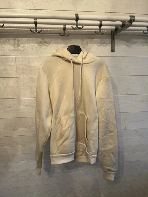 Beige hoodie från Escape - Säljer en beige hoodie från Escape i storlek S. Hoodien har en klassisk huva med dragsko och en stor magficka framtill. Tillverkad i mjukt material som känns skönt mot huden. Perfekt för en chill och avslappnad stil.