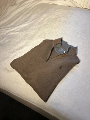 Brun halvzip tröja från Polo Ralph Lauren - Snygg brun tröja med halv dragkedja från Polo Ralph Lauren. Tröjan har en klassisk krage och den ikoniska broderade loggan på bröstet. Perfekt för lager på lager och passar till både jeans och chinos.