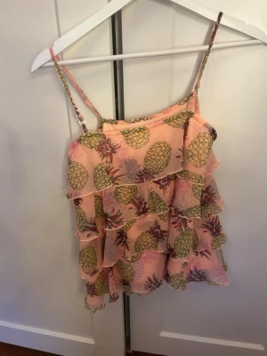 Coral volang tröja med ananas - Fin coralfärgad tröja med volanger och ananasmönster. Pärlor på axelbanden. 