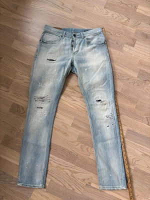 Otroliga dondup George jeans w33  - Superfina populära blå Dondup George jeans säljes i w33. 105 cm total längd och 40 cm breda i midjan. Väldigt snygg tvätt och designade slitningar. Otroliga jeans och grym passform perfekta för alla tillfällen! Jättefint toppskick och tveka inte vid minsta fråga eller fundering!