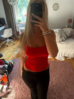 Röd linnetopp med snörning - Trendig röd linnetopp med tunna axelband och snygg snörning i ryggen. Toppen är croppad och har en tight passform som framhäver figuren. Perfekt för att styla med jeans eller kjol för en cool look.