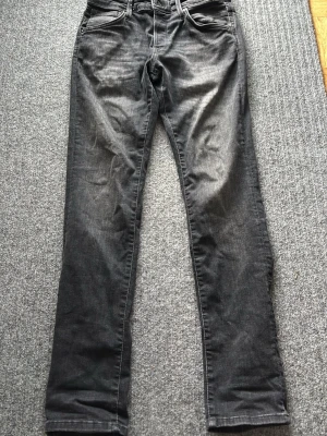 Svarta slim jeans från Jack & Jones - Snygga svarta slim fit jeans från Jack & Jones, modell Glenn. Jeansen har fem fickor, knappgylf och är tillverkade i stretchigt denimtyg för extra komfort. Passformen är smal och benen är raka. Perfekta för en trendig och avslappnad stil.