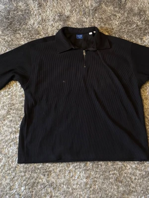 Svart ziptröja från Jack & Jones - Säljer en svart långärmad ziptröja från Jack & Jones Originals. Tröjan har ribbad struktur, krage och halv dragkedja framtill. Perfekt för en avslappnad och stilren look. Passar till det mesta och är enkel att matcha.
