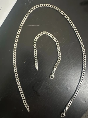 Silverfärgat kedjehalsband - Snyggt halsband i silverfärgad metall med klassisk pansarkedja och droppformade avslut. Halsbandet har en robust karbinhake som gör det enkelt att ta på och av. Perfekt för dig som gillar stilrena och tidlösa accessoarer.