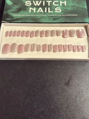 Switch Nails ljusrosa/lila press-on naglar - Säljer ett set press-on naglar från Switch Nails i en mjuk ljusrosa/lila nyans med subtilt skimmer. Naglarna har en naturlig, kort och rundad form och är tillverkade av återvunnet material. Perfekt för dig som vill ha en clean och fräsch look. 30 st varav 10 är använda.