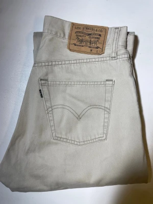 Beiga raka jeans från Levi's - Snygga beiga jeans från Levi's med klassisk femficksmodell och raka ben. Jeansen har en neutral färg som passar till det mesta och är tillverkade i ett slitstarkt bomullstyg. Perfekta för dig som gillar en clean och tidlös stil. Modell:517. Storlek W31, L32
