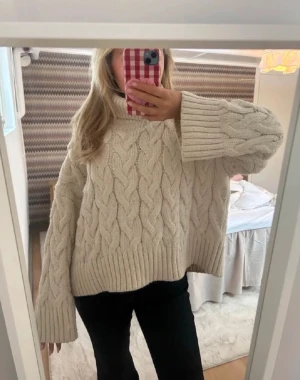 Beige kabelstickad oversized tröja med halvpolokrage - Säljer en beige kabelstickad tröja med oversized passform och breda ärmar. Tröjan har grovstickat mönster och ribbade muddar vid ärmslut och nederkant. Perfekt för lager på lager och riktigt mysig till hösten. Storlek xs passar s💓💓