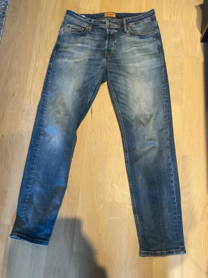 Blå tapered jeans Tapered/Mike - Säljer ett par blå jeans med tapered fit, modellen heter Tapered/Mike. Jeansen har klassisk femficksdesign, snygga slitningar och kontrastsömmar. Perfekta för dig som gillar en avslappnad men ändå stilren look. Skickar inom 24 timmar, priset kan diskuteras☺️