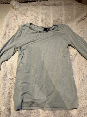 Ljusblå långärmad topp Gina Tricot - En enkel och stilren ljusblå långärmad topp från Gina Tricot. Tillverkad i mjukt material med rund halsringning och normal passform. Perfekt att matcha med jeans eller kjol för en clean look.