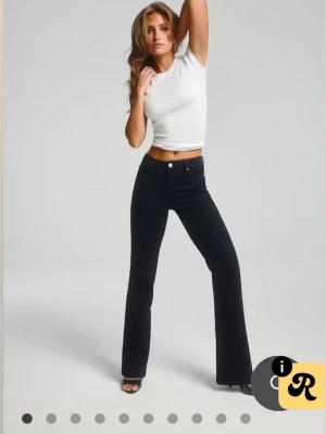 Svarta bootcut jeans med hög midja - Snygga svarta jeans med bootcut passform och låg midja. Jeansen har klassiska  fickor och stängs med knapp och dragkedja. Perfekta för en trendig och avslappnad look. Tillverkade i ett stretchigt denimtyg som sitter bekvämt.