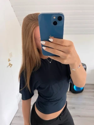 Mörkblå croppad t-shirt - Säljer en enkel och stilren mörkblå croppad t-shirt med normal passform. T-shirten har korta ärmar och rund halsringning. Perfekt till jeans eller mjukisbyxor för en avslappnad look. Använd endast 2 gånger