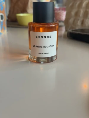 ESSNCE Orange Blossom parfym - Fräsch Eau de Parfum från ESSNCE med doft av orange blossom. Flaskan är rund i genomskinligt glas med svart matt kork och har en stilren vit etikett. Innehåller noter av citrus, bergamott och vanilj. Helt ny, aldrig använd 