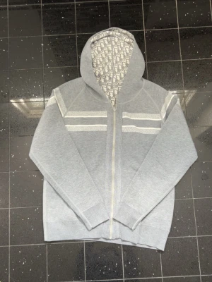 Grå hoodie med mönstrad luva  - Snygg grå hoodie. Tillverkad i mjukt material, perfekt för en trendig och avslappnad look.