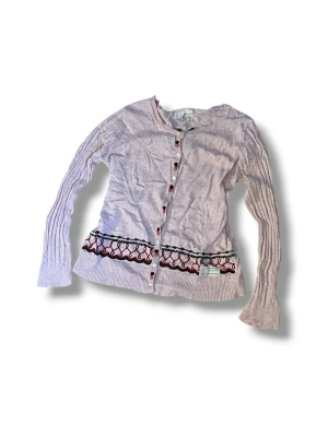 Odd Molly kofta - Ljusrosa kofta från Odd Molly med långa ärmar och ribbade muddar. Broderier längs nederkanten sam knappar framtill. Storlek 1 vilket motsvarar S.