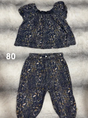 Pompdelux set - Tvådelat set med kortärmad topp och byxa. Toppen har resår vid halsen och byxan har resår i midja och benslut. Perfekt för en trendig och bekväm look.🌸 Fint använt skick. Storlek 80