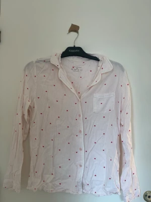 Ljusrosa pyjamaströja med hjärtan - Söt ljusrosa pyjamaströja från Primark med tunna vita ränder och små röda hjärtan över hela plagget i storlek XS.