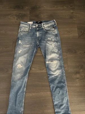  Replay Anbass jeans - Säljer ett par blå jeans från Replay i modellen Anbass. Jeansen har en slim fit passform, slitningar och hål på benen för en trendig, avslappnad look. Perfekta för dig som gillar streetstyle.  Hör gärna av dig vid funderingar 😁