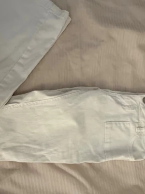 Vita raka jeans med låg midja - Säljer ett par vita jeans med rak passform och låg midja. Jeansen har  dubbla silverknappar i midjan. 