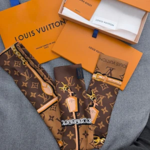 Louis Vuitton brun monogram silkessjal - Lyxig brun silkessjal från Louis Vuitton med klassiskt monogrammönster. Sjalen har kedje- och bältesmotiv samt logotyptryck. Perfekt accessoar för att lyfta din outfit med exklusiv känsla.
