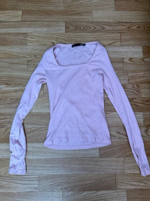Ljusrosa långärmad topp - Söt ljusrosa topp med lång ärm och fyrkantig ringning. Tillverkad i mjuk bomullsmix som känns skön mot huden. Perfekt att styla med jeans eller kjol för en clean och enkel look.