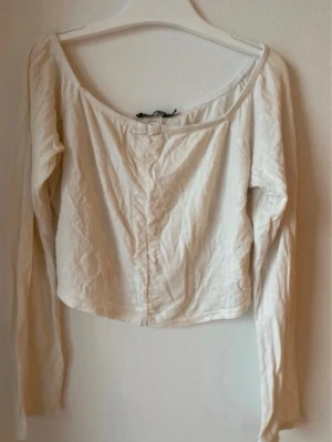 Vit off shoulder topp - Säljer en vit off shoulder topp med långa ärmar. Toppen har en enkel och stilren design som passar perfekt till jeans eller kjol.