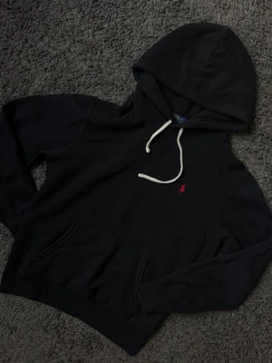 Svart hoodie från Polo Ralph Lauren - Snygg svart hoodie från Polo Ralph Lauren med klassisk röd logga.  I fint skick! Storlek S.