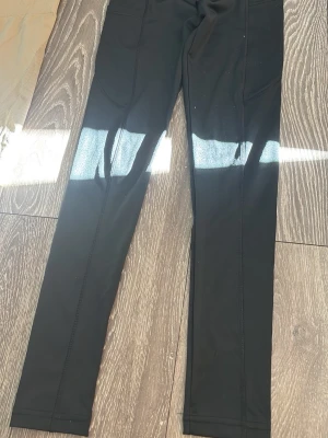Svarta leggings med fickor - Snygga svarta leggings med smal passform och praktiska sidofickor. Tillverkade i stretchigt material som sitter bekvämt och följer kroppen. Perfekta till både träning och chill. Matcha med en oversized hoodie eller crop top för en trendig look.