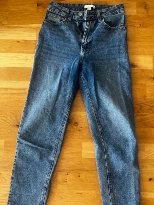 Blå mom jeans med hög midja - Ett par klassiska blå mom jeans med hög midja och raka ben. 