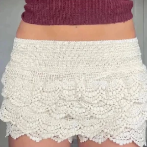 Spetsshorts  - Säljer ett par  virkade shorts med flera lager volangdetaljer. De har en hög midja och är perfekta för sommaren. Materialet känns luftigt och ger en bohemisk vibe. Passformen är normal och de är riktigt snygga till både crop tops och linnen.