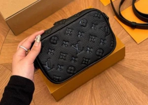 Louis Vuitton väska axelväska  - Snygg svart axelväska från Louis Vuitton i präglat läder med klassiskt monogrammönster. Väskan har justerbar axelrem, dragkedja och flera fack. Perfekt för dig som vill ha en stilren och lyxig accessoar till din outfit.