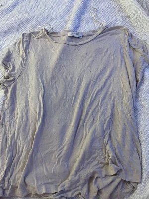 Beige kortärmad t-shirt från Lindex - En enkel och mjuk beige t-shirt från Lindex med rund hals och korta ärmar. Perfekt basplagg till garderoben och lätt att matcha med olika stilar. Tillverkad i ett tunt och bekvämt material.