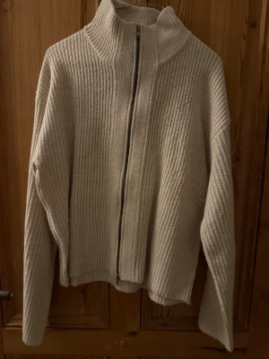 Beige ribbstickad ziptröja - Säljer en beige ribbstickad tröja med dragkedja framtill. Aldrig använd 