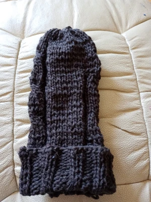 Mörkbrun stickad mössa - Säljer en mörkbrun stickad mössa med bred uppvikt kant och grovt mönster. Mössan är handstickad i tjockt garn och har en klassisk, lite längre modell som ger en avslappnad look. Perfekt för kalla dagar när du vill hålla dig varm och snygg.