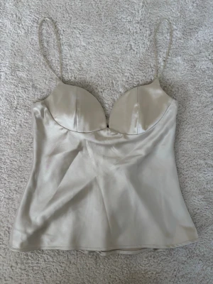 Satin topp - Super fin satin topp i champagne färg, lite liten i storlek enligt mig så passar mer som en XS, dragkedja på sidan, vadderade kupor