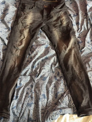 Dolce Gabbana jeans - Säljer ett par svarta skinny jeans från Dolce & Gabbana med slitningar och små dekorativa nitar framtill. Jeansen har klassisk femficksmodell, låg midja och detaljerade bakfickor med metallplatta. Materialet är stretchigt denim för skön passform.