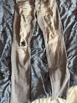 Dsquared2 jeans - Säljer ett par grå jeans från Dsquared2 med distressed detaljer och hål på knäna. Jeansen har raka ben, klassisk femficksmodell och coola slitningar som ger en edgy look. Perfekta för dig som gillar streetstyle och vill sticka ut. Står w29 l34 men passar mig som är 184 för referens 