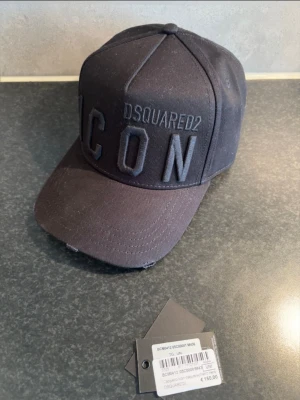 Svart Dsquared2 ICON keps - Dsquared2 ICON-keps i svart  Säljer min svarta ICON-keps från Dsquared2 då passformen tyvärr inte passar mig. Kepsen är därför endast använd ett fåtal gånger och har mest blivit liggande.  Klassisk svart modell med ton-i-ton broderad DSQUARED2 ICON-logga framtill.  Originaltags finns kvar och kvitto från Miinto finns, vilket kan visas vid köp.  • Färg: Svart • Modell: ICON • Storlek: One Size • Originaltags finns • Kvitto finns • Nypris enligt tagg: €150 • Sparsamt använd