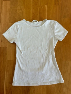 Vit ribbad t-shirt med kort ärm - Säljer denna basic vita ribbade T-shirten ifrån HM stl S💞 Tröjan har inga tecken på användning. Skriv för fler bilder.