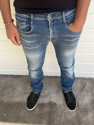 Replay Jeans Anbass blå - Hej! Blå detaljrika Replay Anbass jeans med snygg tvätt säljes. Som referens är modellen på bilden 173cm och väger 74kg. Passformen är slim och har den mest populära modellen Anbass. Storlek: W33/L32. Materialet består av 85% bomull, 10% polyester och 5% elastan. Hör gärna av dig vid intresse av köp! 🙌mvh