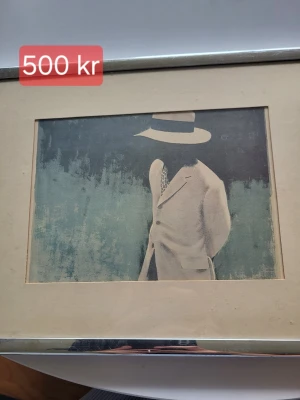 Tavla med motiv av man i hatt - Säljer en inramad tavla med konstmotiv av en man i ljus kostym och hatt mot en blågrön bakgrund. Tavlan har en bred beige passepartout och ram i metall. Perfekt för dig som gillar unik konst och vill ha något stilrent på väggen.