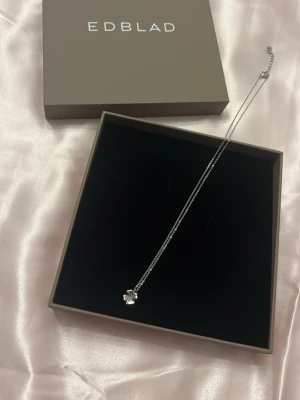 Silverhalsband med klöver från Edblad - Snyggt halsband i silver från Edblad med en liten klöver berlock. Kedjan är tunn och elegant, perfekt för att ge en subtil touch till din outfit. Kommer i original ask vilket gör det till en fin present.