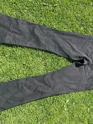 Svarta raka jeans i storlek 36 - Säljer ett par svarta jeans med lite utsvängda ben och klassiska fem fickor. Jeansen har bälteshällor, knappgylf och är tillverkade i ett slitstarkt denimtyg. Perfekta till en avslappnad och trendig look.