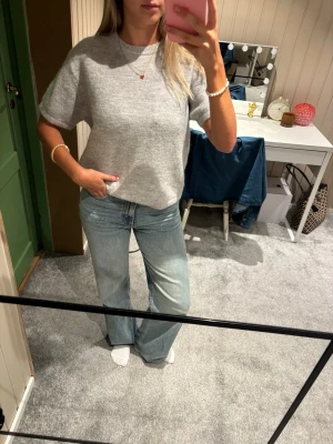 Ljusgrå stickad t-shirt - Kortärmad stickad tröja i ljusgrått med rund hals. Från ginatricot. Aldrig använd.